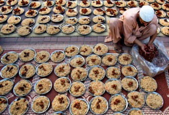 A man arranges plates with meals for Iftar, or breaking of the fast, donated by an Islamic seminary during the first day of Ramadan in Islamabad, Pakistan, on July 21, 2012.